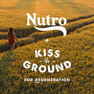 woman walking through field at dusk with Nutro and Kiss The Ground logos